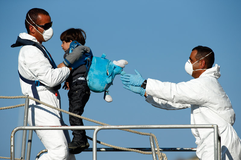  Armed Forces of Malta (AFM) sailors disembark a would-be immigrant child from an AFM offshore patrol vessel at the AFM Maritime Squadron base at Haywharf in Valletta's Marsamxett Harbour October 29, 2013. 41 immigrants, claiming to be Syrians and Palestinians, were rescued from a boat in distress 89 nautical miles south of Malta in a joint operation between Maltese and Italian forces. 