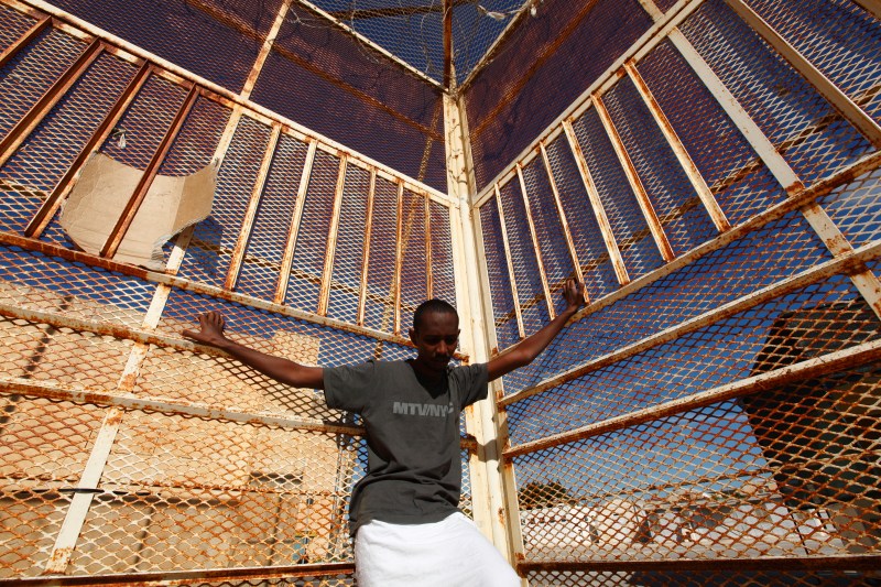 A 29-year-old Eritrean migrant stands against a fence at the Safi barracks detention centre for immigrants in Safi, outside Valletta, October 22, 2013. 