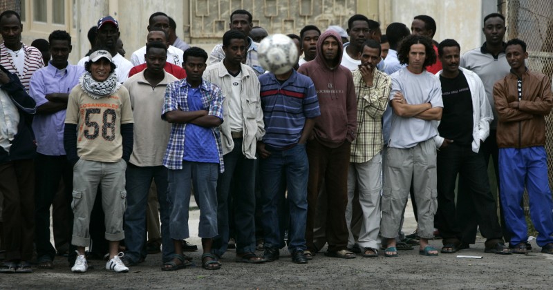 Migrants watch others from Ivory Coast and Somalia play in their version of a World Cup soccer final at the Marsa open centre for refugees outside Valletta June 11, 2006. Residents of the open centre from several African nations took part in the five-aside tournament as a way of joining in the world-wide celebration of the 2006 FIFA World Cup in Germany.