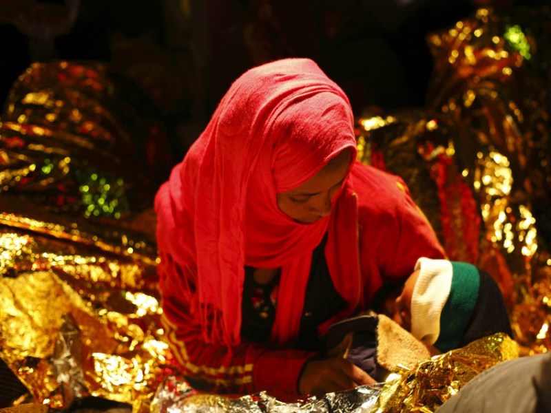 An exhausted migrant cradles her two year old son while sitting on the deck of an Armed Forces of Malta (AFM) patrol boat after berthing at the AFM Maritime Squadron base at Haywharf in Valletta's Marsamxett Harbour early May 31, 2012. Sixty-five migrants, most of who claim to be from Eritrea, were rescued by the AFM 74 nautical miles south of Malta when their rubber dinghy started taking on water while on its way to reach European soil from Africa, authorities said. 