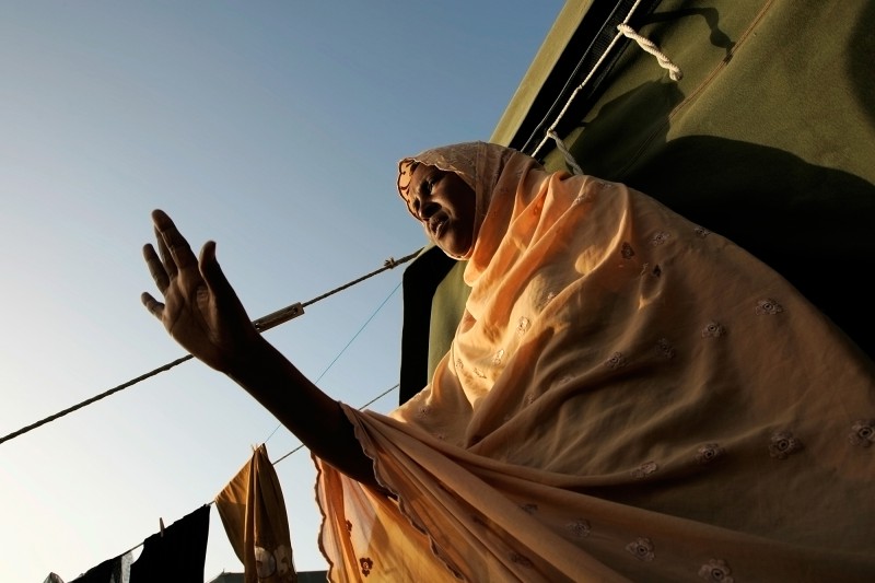 A Somali woman waves to a friend as she comes out of the tent they share at Hal Far Tent Village open centre for migrants at Hal Far outside Valletta, June 6, 2007. Many asylum seekers who are granted protection are released from detention into one of the open centres. Some opt to move to the community right away