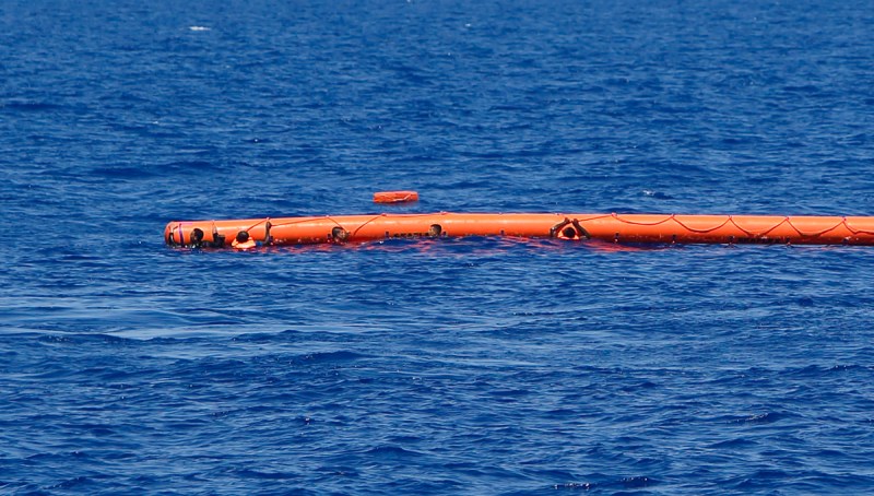 Migrants hang onto a flotation device during a rescue operation off the coast of Libya