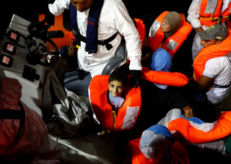 A migrant child smiles as he waits to be transferred from the Migrant Offshore Aid Station (MOAS) ship MV Phoenix to the Norwegian ship Siem Pilot off the coast of Libya